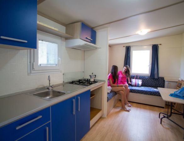 Cucina blu con due persone sedute su un divano in un piccolo soggiorno.