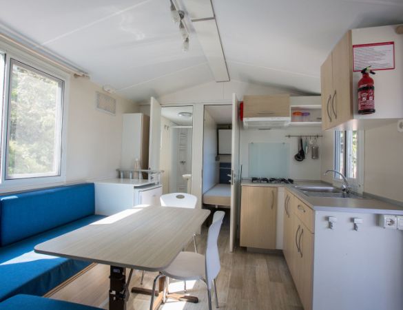 Interno di una casa mobile con cucina, tavolo da pranzo e divano blu.