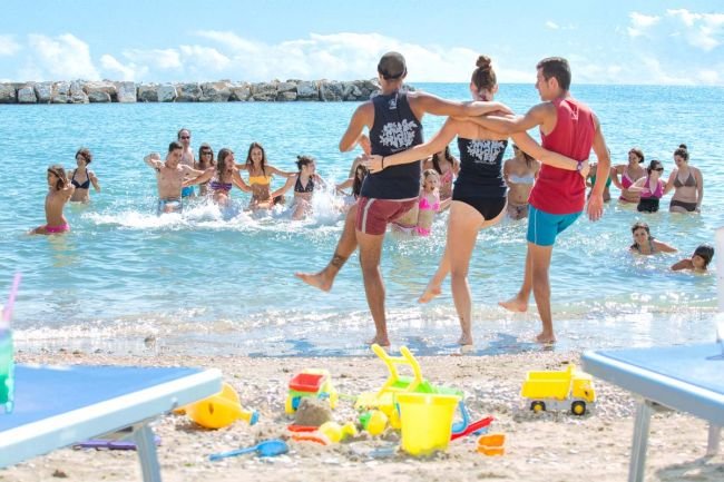 Persone giocano e si divertono in mare, con giochi sulla spiaggia.