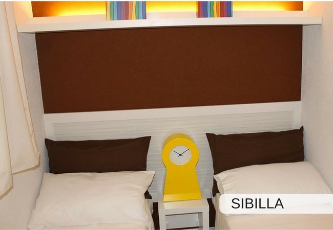 Due letti singoli con cuscini marroni e orologio giallo.