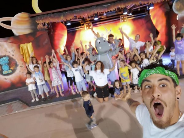 Bambini e adulti festeggiano davanti a un palco.