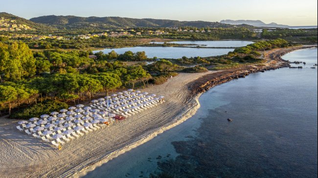 Spiaggia con ombrelloni bianchi e mare azzurro.