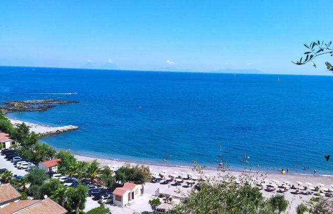 Una spiaggia con ombrelloni e mare blu.