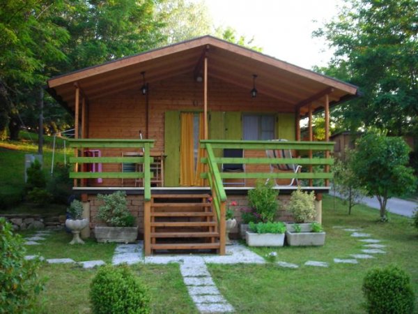 Casetta di legno con terrazza e giardino.