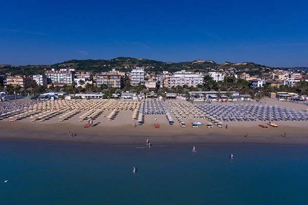 Spiaggia sabbiosa con ombrelloni e bagnanti.