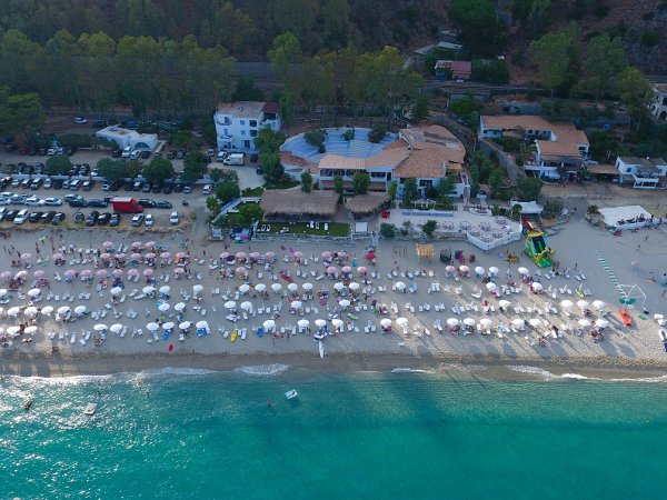 Vista aerea di spiaggia affollata con ombrelloni colorati.