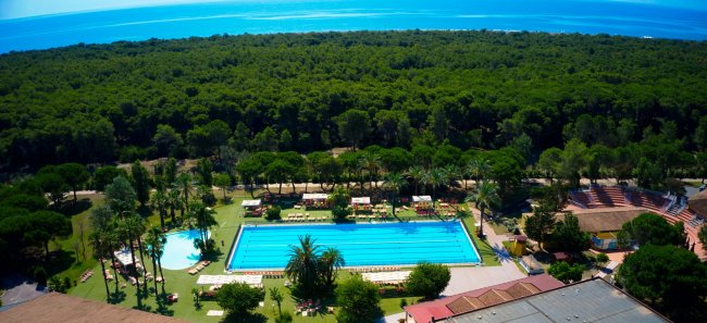 Piscina all'aperto circondata da pineta e vista sul mare.