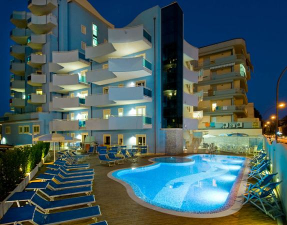 Edificio moderno illuminato con piscina e lettini.
