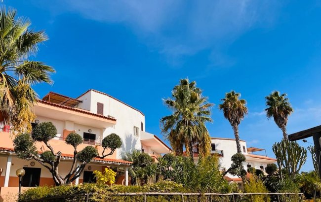 Edificio bianco con palme e cielo azzurro.