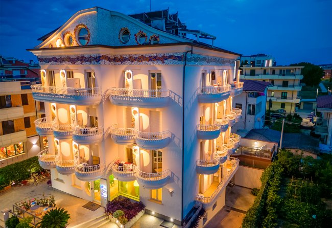 Edificio bianco illuminato di notte con balconi arrotondati.
