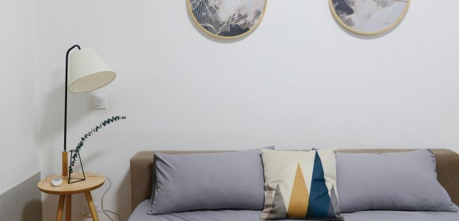 Divano grigio con cuscini, lampada e arte murale tonda.