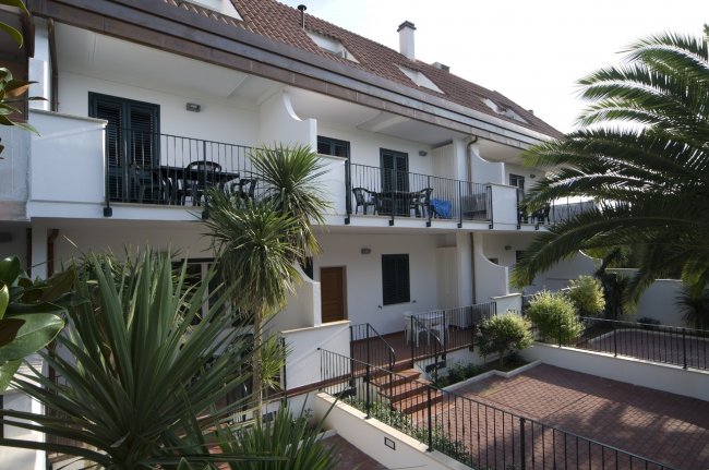 Edificio residenziale moderno con terrazze e palme.