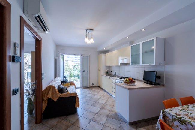 Salotto moderno con cucina e porta finestra sul balcone.