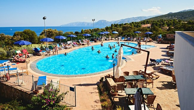 Piscina all'aperto con lettini e vista sul mare.