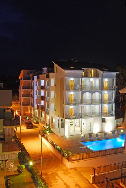 Hotel illuminato di notte con piscina.