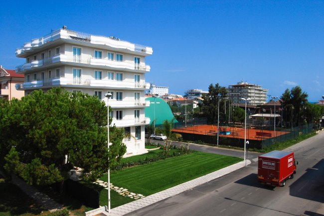 Edificio bianco vicino a un campo da tennis.