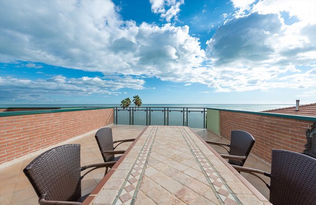 Terrazza con tavolo, sedie e vista mare.