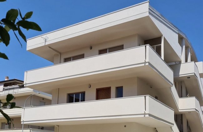 Edificio moderno con balconi bianchi su tre piani.