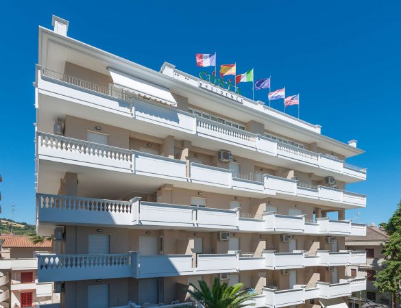 Edificio bianco a più piani con bandiere sul tetto.