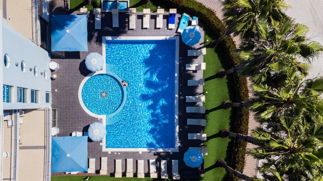 Veduta aerea di una piscina con lettini e ombrelloni.