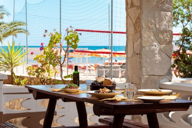 Tavolo all'aperto con piatti, vista mare.