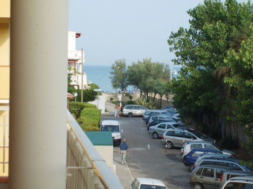 Vista su strada con auto e mare all'orizzonte.