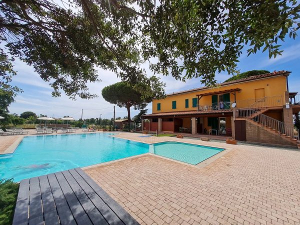 Villa gialla accanto a una grande piscina.
