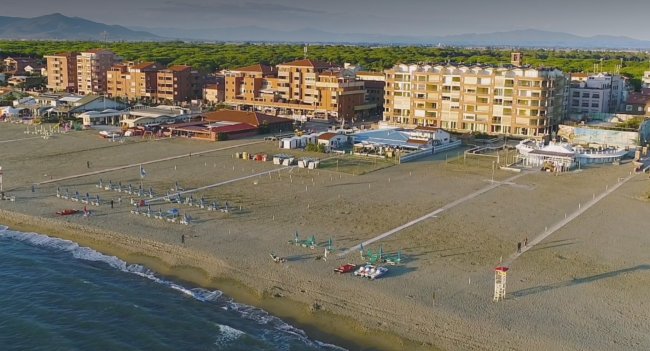 Spiaggia con edifici, ombrelloni e mare calmo.