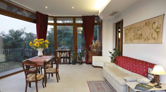 Sala con divano, tavolo in legno e finestre ampie.