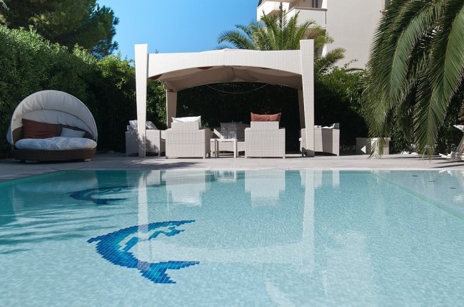 Piscina con mosaico di delfino e gazebo.
