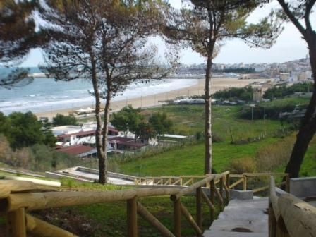 Scalinata in legno che scende verso una spiaggia, con vista sulla costa.