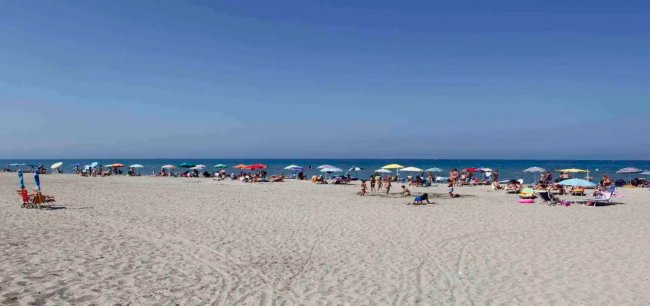 Spiaggia affollata con ombrelloni colorati.