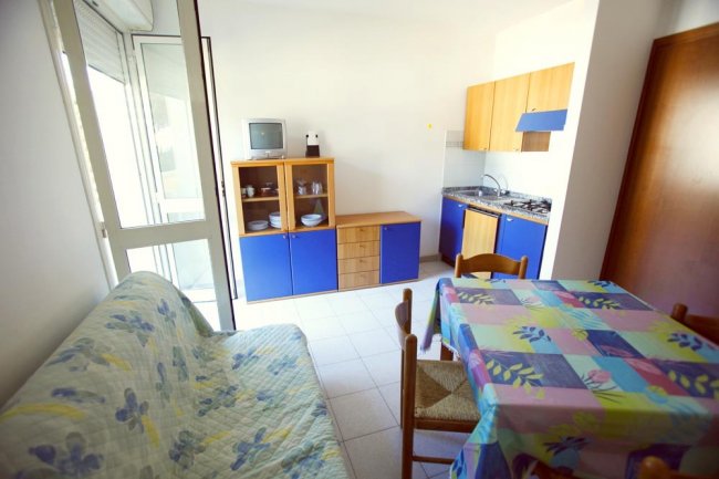 Cucina con tavolo colorato e divano a fiori.