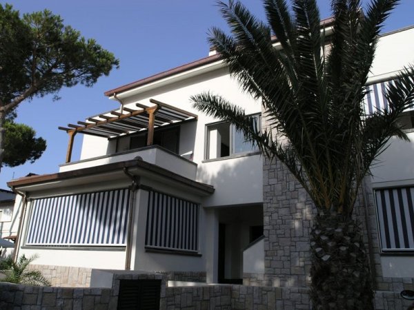 Villa bianca con verande e palme, cielo limpido.
