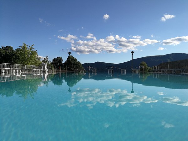 Piscina con riflessi di nuvole e montagne.