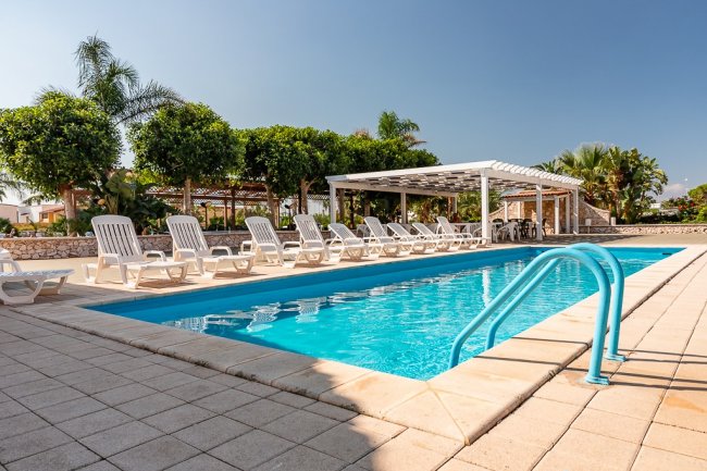 Piscina all'aperto con sedie a sdraio.