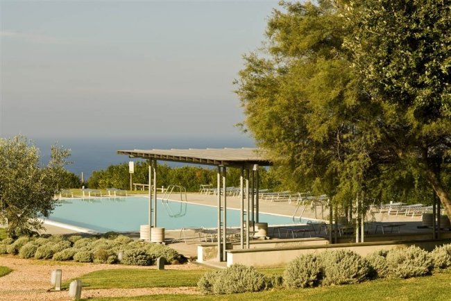 Piscina circondata da alberi con vista sul mare.