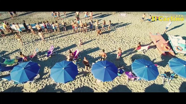 Spiaggia affollata con ombrelloni blu.