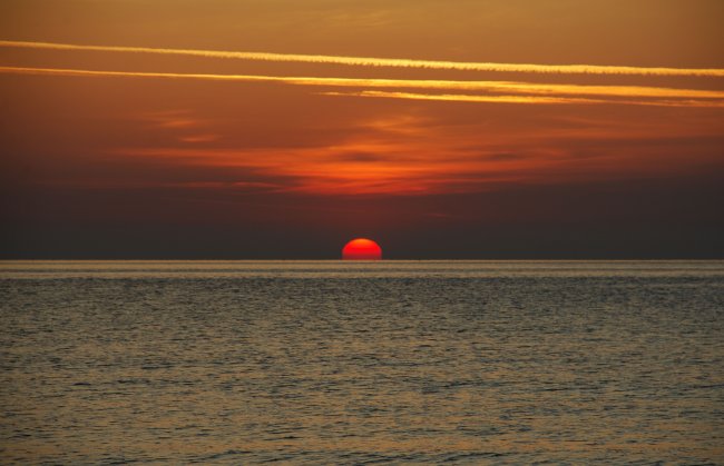 Tramonto sul mare con cielo arancione.