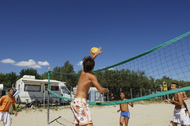 Ragazzi giocano a beach volley sulla sabbia.