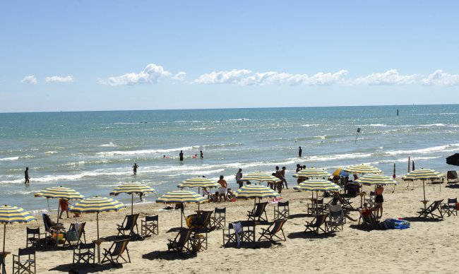 Spiaggia con ombrelloni, sedie e bagnanti.