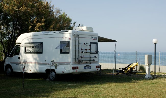 Camper bianco parcheggiato vicino al mare.