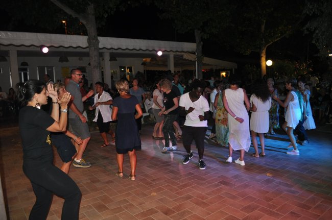 Persone che ballano all'aperto su una pista illuminata.