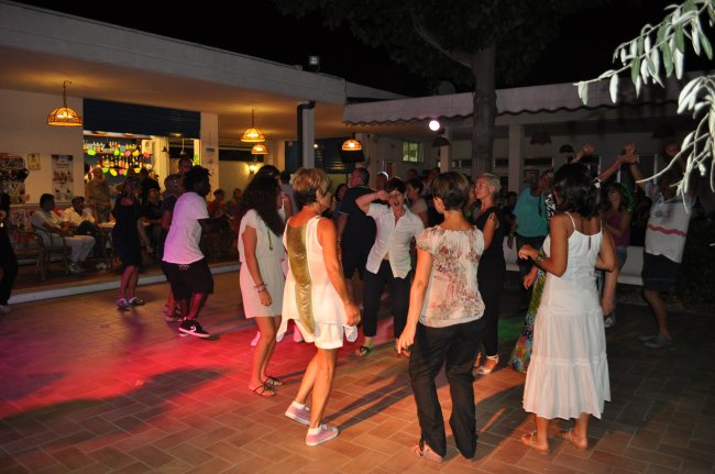 Gruppo di persone che ballano sulla pista illuminata di sera.