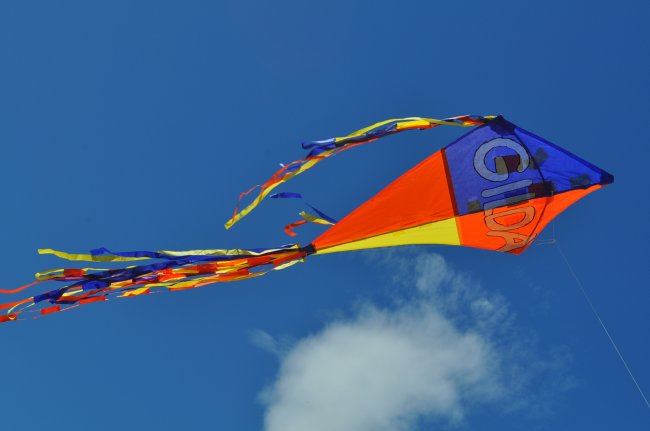 Aquilone colorato con code, vola in cielo azzurro.