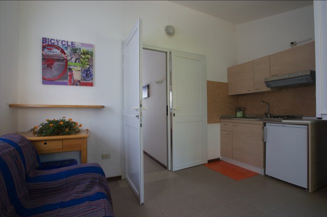 Cucina semplice con divano e porta aperta.