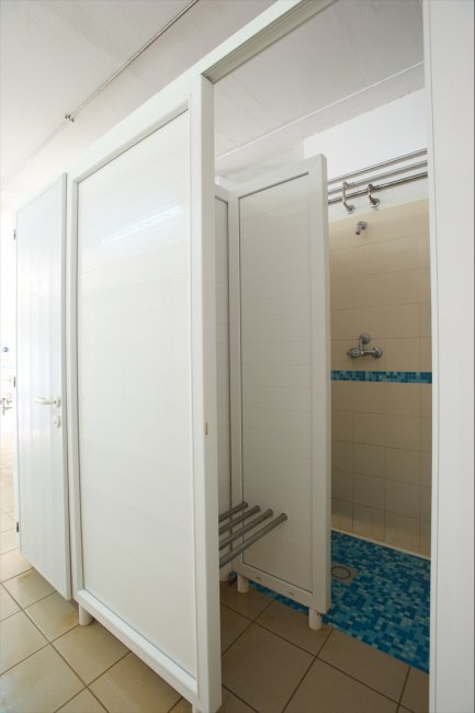 Doccia con piastrelle blu e porta bianca.