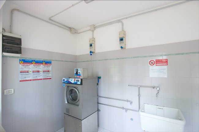 Lavanderia con lavatrice e lavandino bianchi.