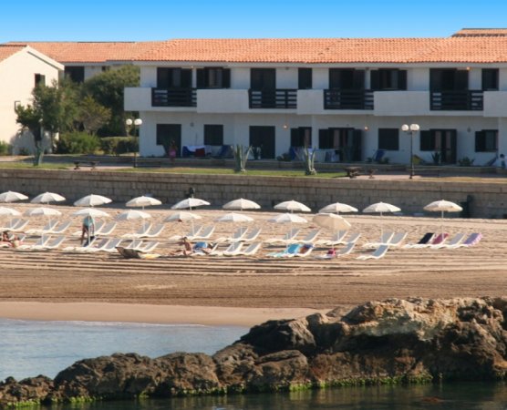 Spiaggia con sdraio e ombrelloni davanti a un edificio.
