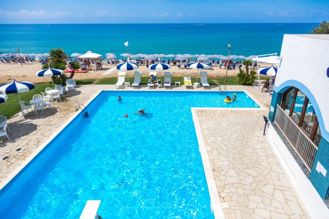 Piscina con ombrelloni, lettini e vista mare.